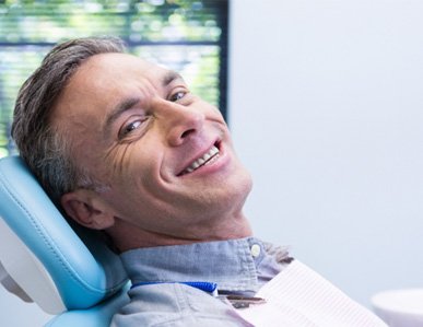 Middle aged man in dentist’s chair smiling  