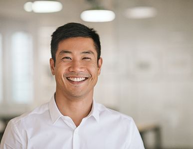 Smiling man with white button-up shirt standing in office