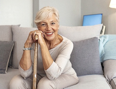 Woman on couch smiling with dentures in Superior