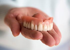 A closeup of a hand holding a removable denture
