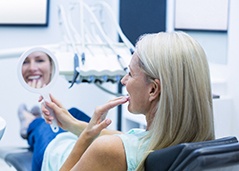 Woman smiling in mirror at dentist's office