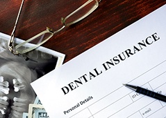Dental insurance paperwork lying on money and X-rays