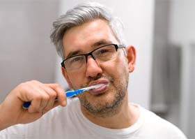 man brushing his dental implants in Superior