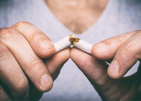 Closeup of patient with dental implants in Superior breaking a cigarette