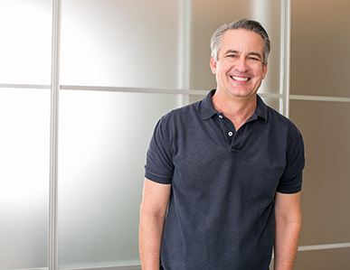 Man with dental implants in Superior smiling in greyish blue polo