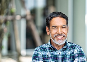 Middle-aged man in plaid shirt smiling while standing outside