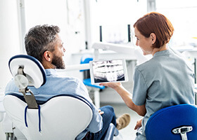 implant dentist and patient discussing how dental implants work