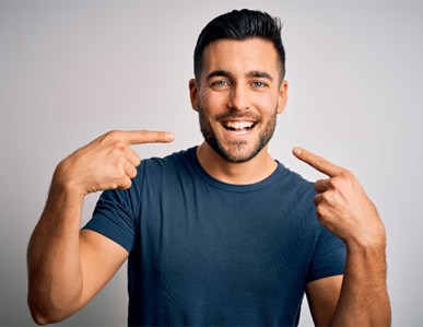 A young smiling man pointing at himself