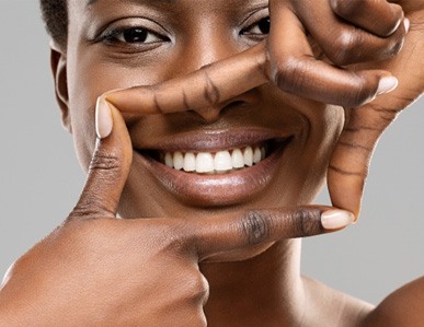 A woman framing her smile with her fingers