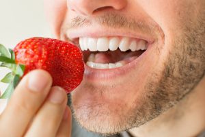 man white teeth strawberries