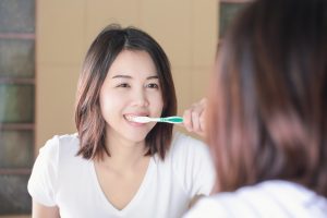 woman brushing her teeth in mirror