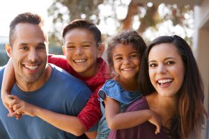 Family smiling together outside after seeing dentist in Superior 