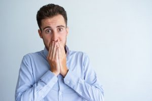 Man with black line around dental crown covers his mouth