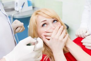 Woman embarrased at the dentist covers her mouth