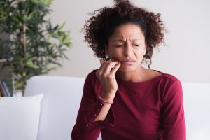 Woman with gum disease touches her jaw