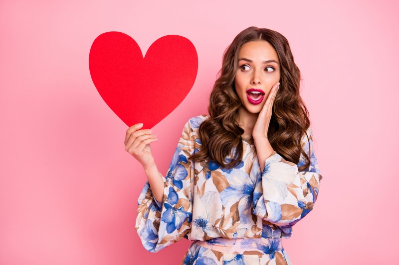 Woman holding up cutout of red heart