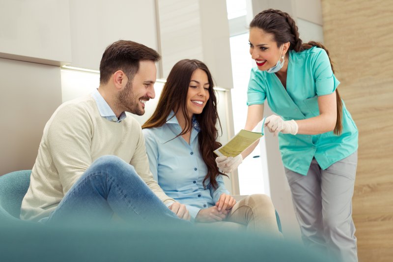 Dental assistant talking to couple in dental office