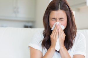 Woman in white t-shirt sneezing