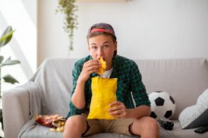 teenager watching sports eating unhealthy food
