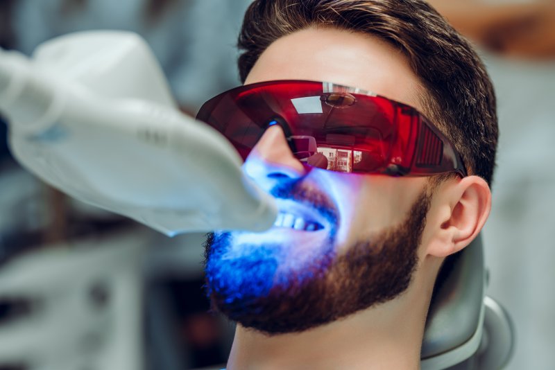 Man having teeth whitened by UV whitening device.