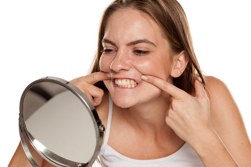 Patient checking teeth for cavities in mirror