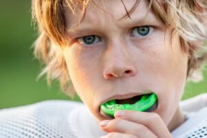Young football player putting in mouthguard. 