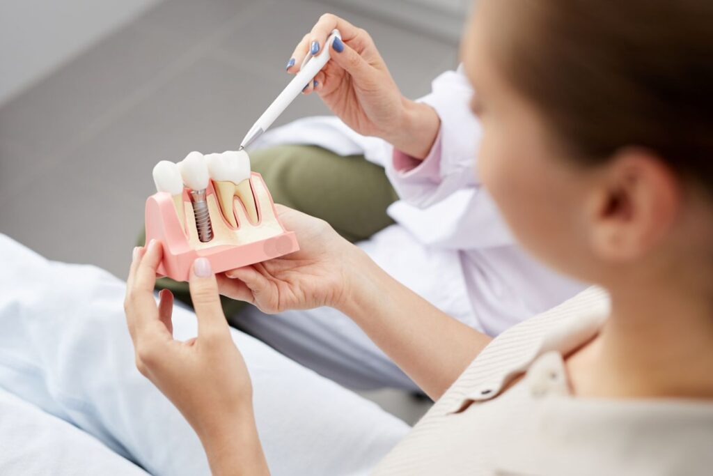 A dentist showing a model of a dental implant to a patient