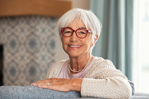 Senior woman in glasses sitting on chair
